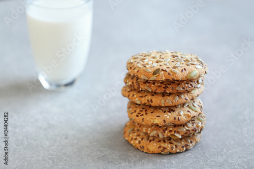 Delicious cereal cookies with glass of milk on color background