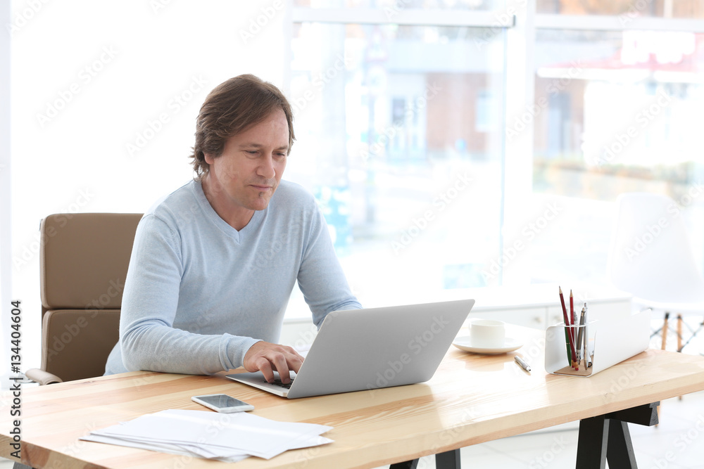 Mature man working with laptop in office Mature man working with laptop in office