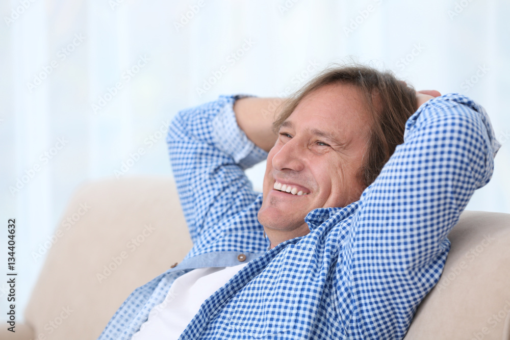 Positive mature man sitting on sofa at home Positive mature man sitting on sofa at home