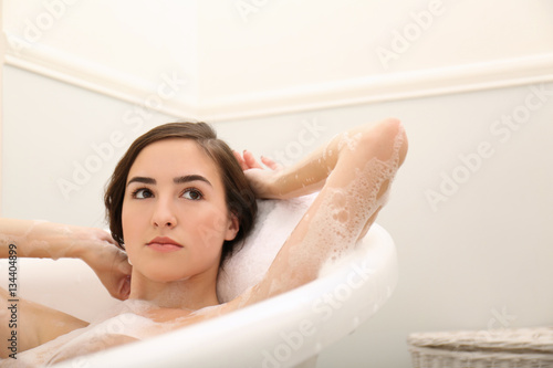 Young beautiful woman taking relaxing bath with foam  closeup