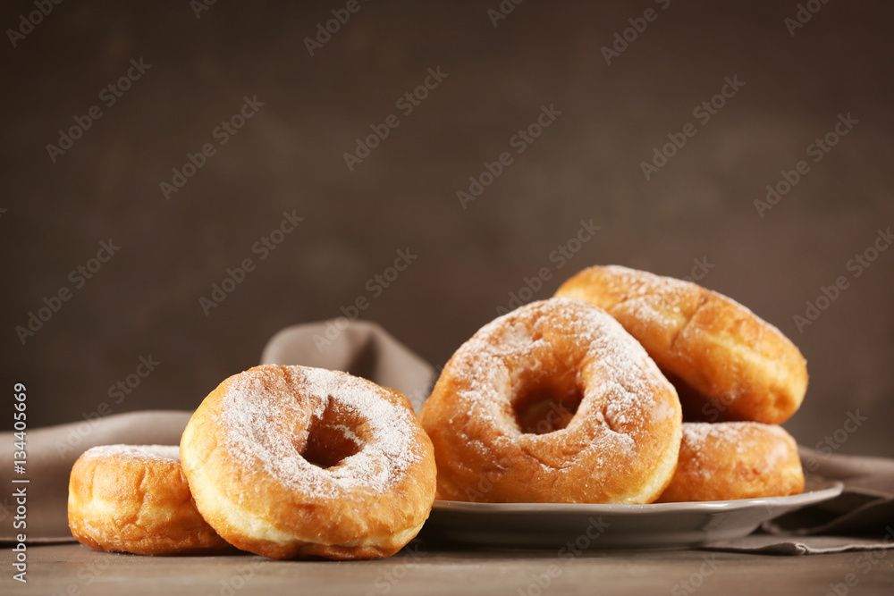 Tasty donuts with powdered sugar on table