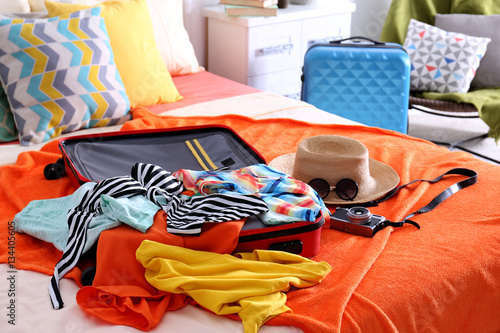 Fotografie Open suitcase with clothes and personal things packed for travelling