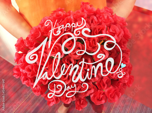 Happy Valentine's Day word lettering on red roses bouquet in woman hand with bokehn effect photo