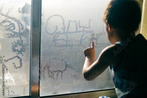Hand draws on cold fogged window background, closeup image