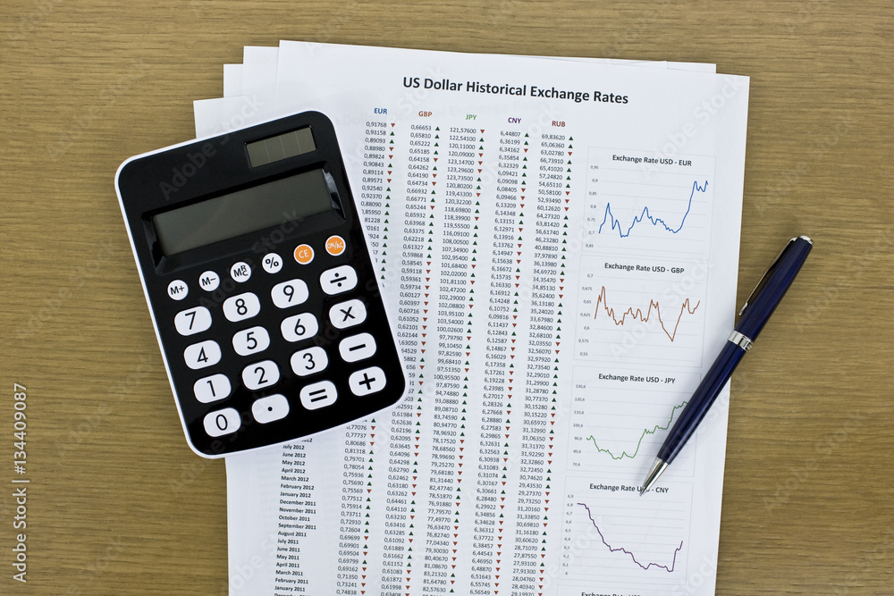 Calculator and exchange rates reports on desk. Top view. Calculator and exchange rates reports on desk. Top view.