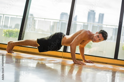 Handsome young man doing abs exercises on mat