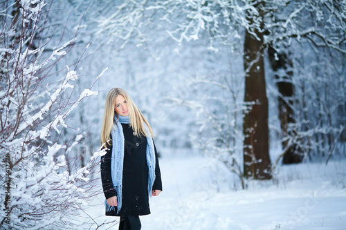 Beautiful young girl smiling and walking in the street. Beautiful snowy cold winter. Holiday mood.