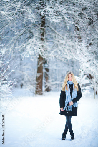 Winter. Young girl walking snowy forest and smiling at the camera. Great mood.