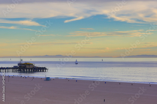 Fototapeta Naklejka Na Ścianę i Meble -  The Pacific Ocean is during sunset. Landscape of beach has pier and boats, the USA, Santa Monica. 