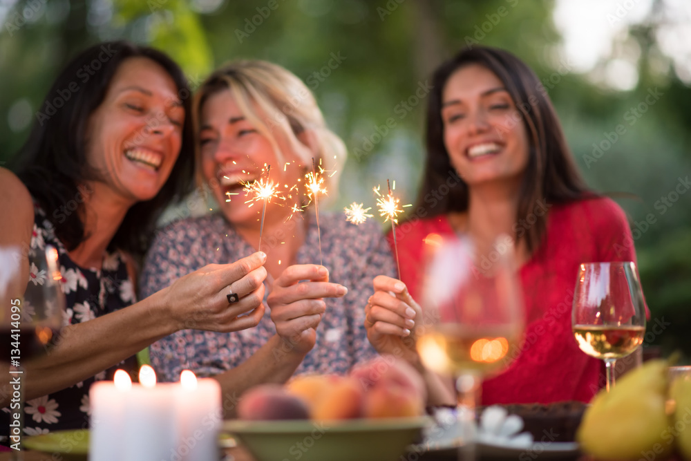 Three beautiful women having fun while they hold spark sticks