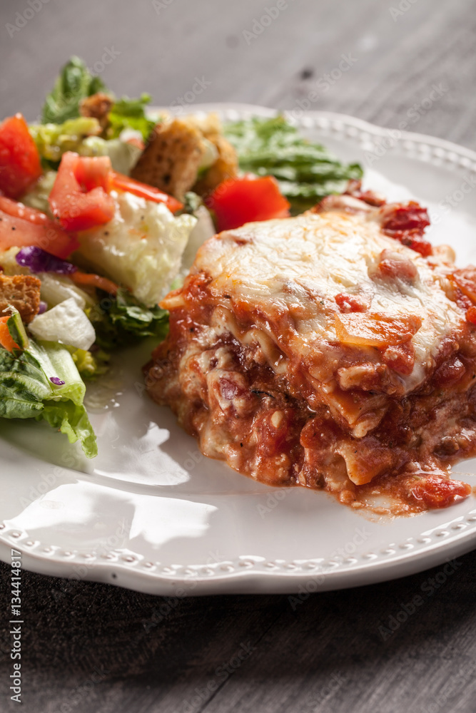 Homemade Italian four cheese lasagna with a side salad close view Homemade Italian four cheese lasagna with a side salad close view