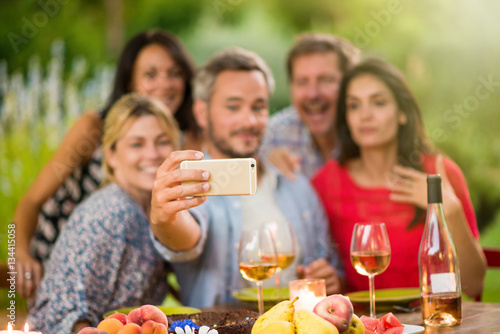 Friends taking a selfie on a terrace by a summer evening