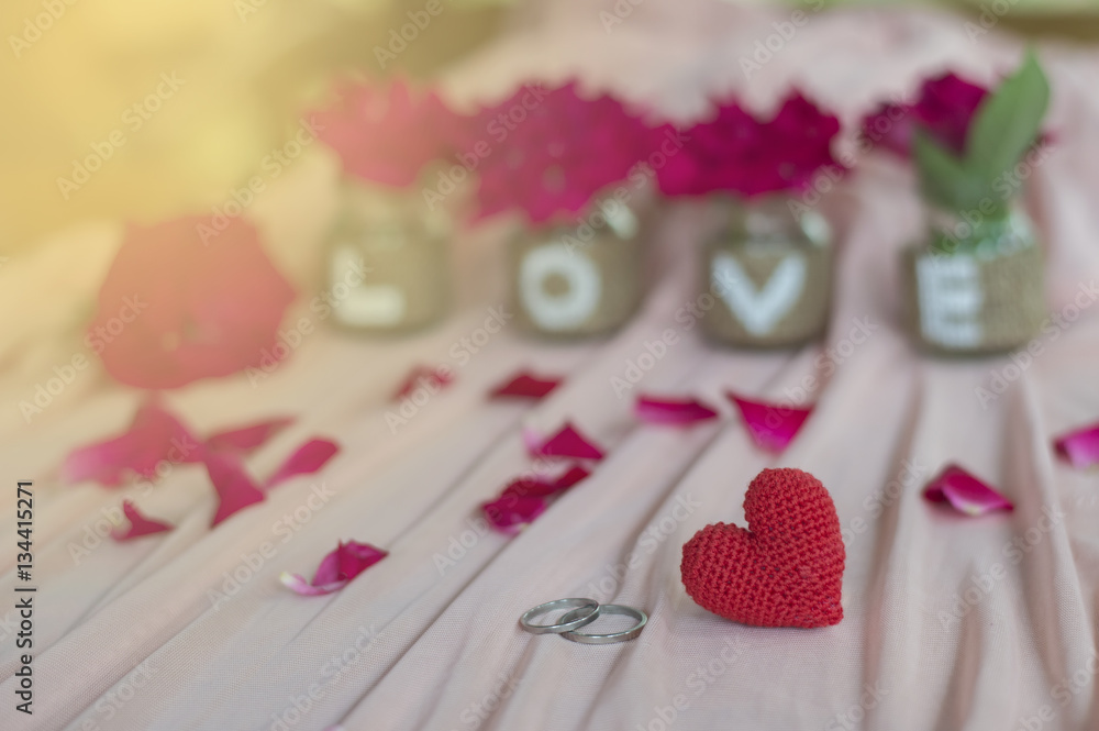 Obraz premium Close up of wedding rings and red heart handmade with love on the bottle for Valentine's day or wedding background