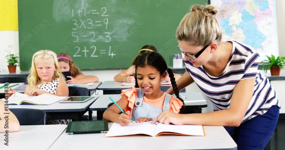 Teacher helping schoolgirl with their homework in classroom at school 4k Teacher helping schoolgirl with their homework in classroom at school 4k