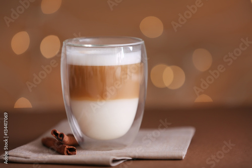 Cup of fresh coffee and cinnamon on blurred background
