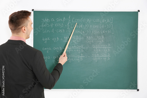 Young male teacher beside b...