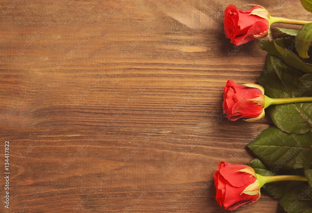 Beautiful red roses on wooden background