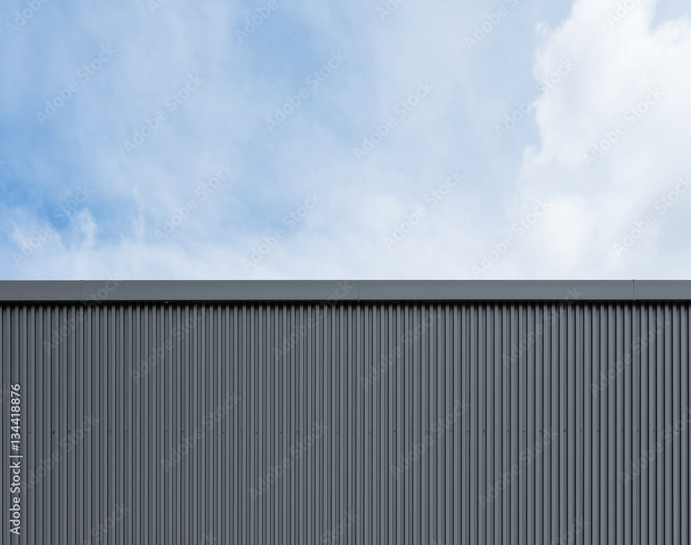 Corrugated factory industry wall on blue sky with clouds Corrugated factory industry wall on blue sky with clouds