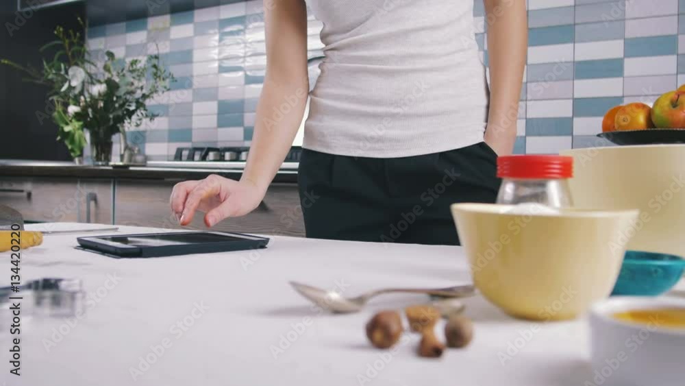 Woman using the tablet at the kitchen, close up, pan Woman using the tablet at the kitchen, close up, pan