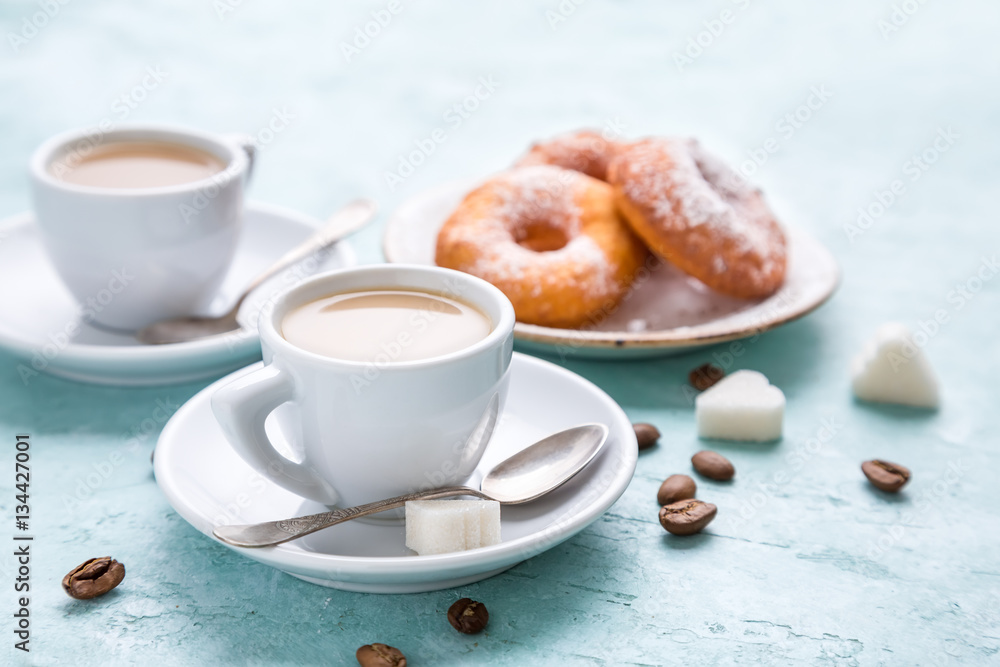 Two cups of coffee with cream and homemade donuts