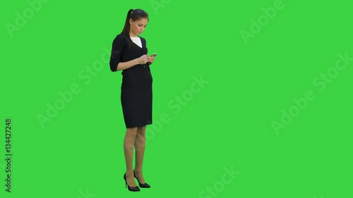 Young businesswoman checking her mobile phone while walking on a Green Screen, Chroma Key