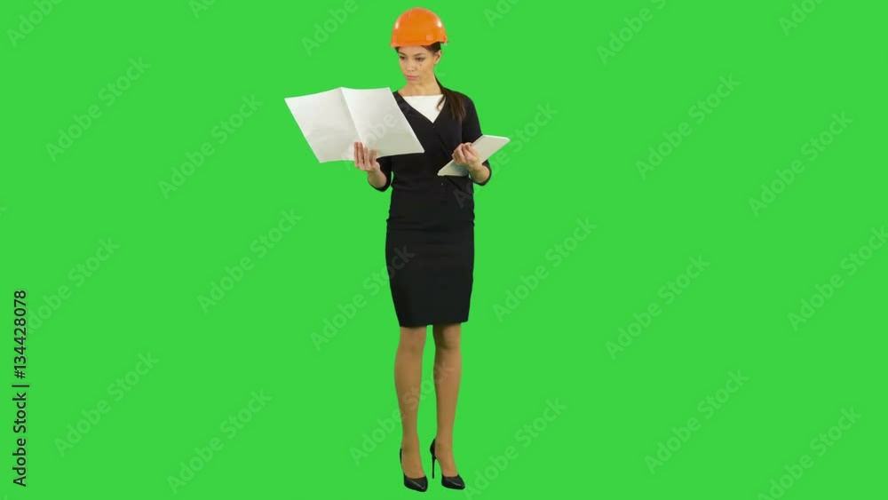 Female construction engineer in helmet holding blueprints and using tablet on a Green Screen, Chroma Key Female construction engineer in helmet holding blueprints and using tablet on a Green Screen, Chroma Key