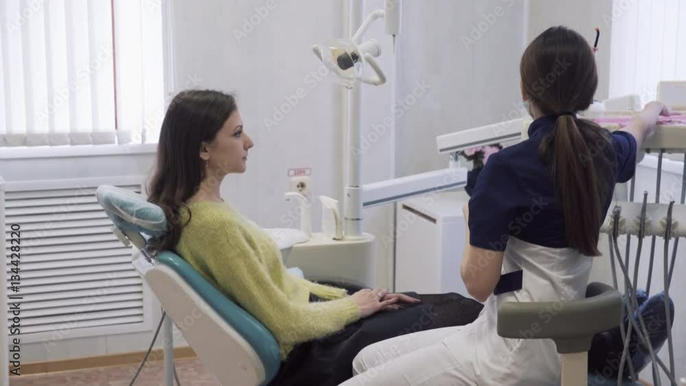 beautiful female dentist prepares the patient to the procedures in the dental clinic, puts on chest sterile cloth. Concept of heatlhy life. beautiful female dentist prepares the patient to the procedures in the dental clinic, puts on chest sterile cloth. Concept of heatlhy life.