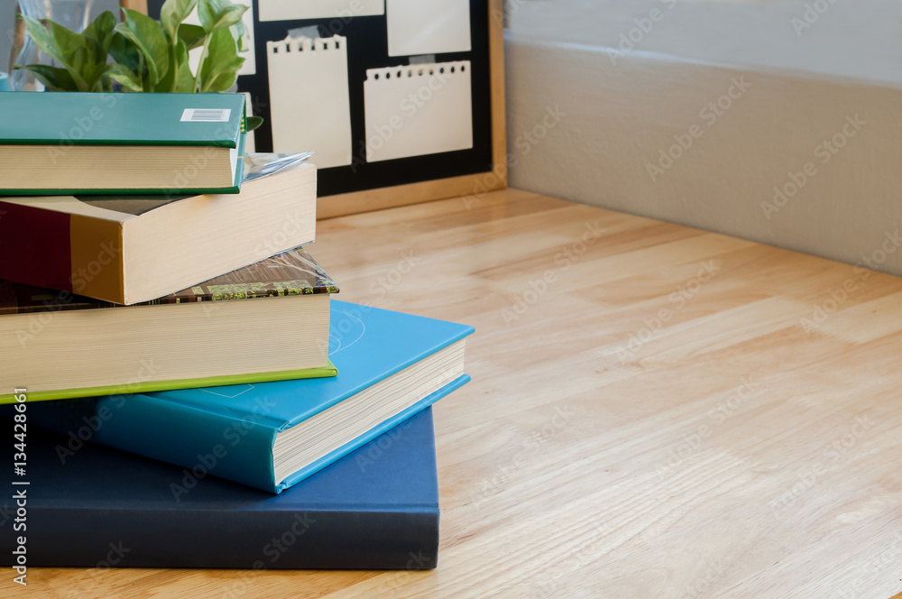 Naklejka premium Closeup Stack of colorful books on wooden table with blackboard. Time to learn and read concept.