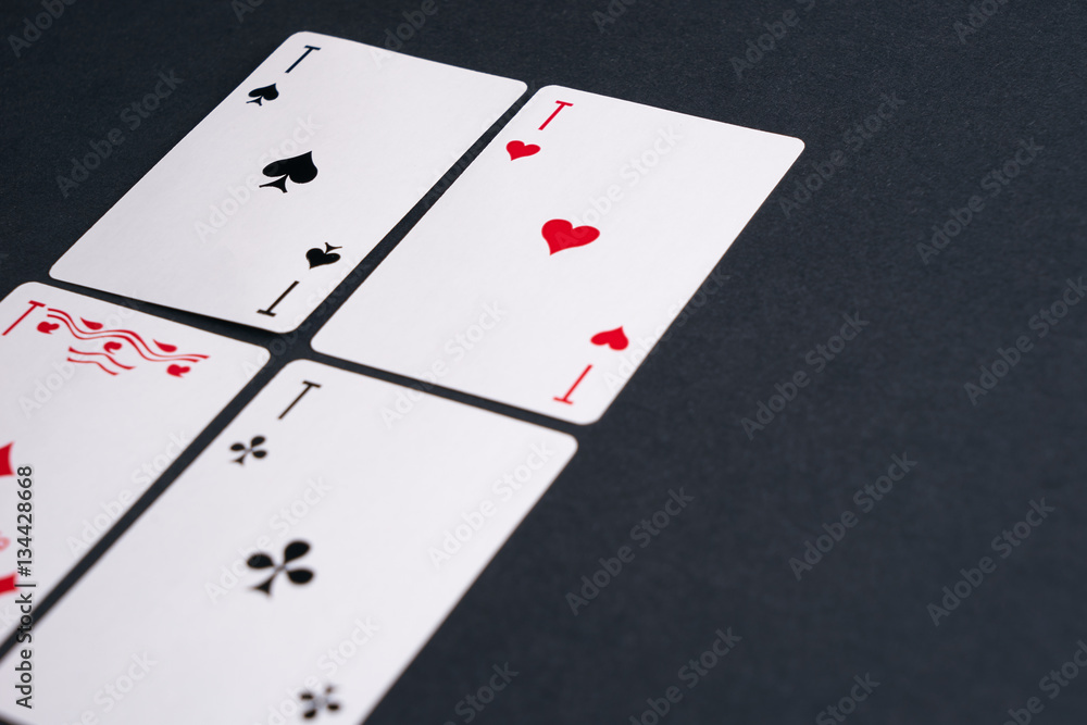 High Angle View of Four Playing Cards Spread Out on Dark Background Showing Aces from Each Suit - Hearts, Clubs, Spades and Diamonds High Angle View of Four Playing Cards Spread Out on Dark Background Showing Aces from Each Suit - Hearts, Clubs, Spades and Diamonds