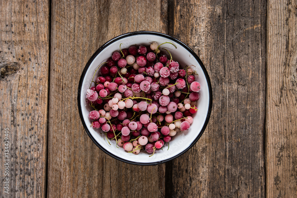 frozen berries, white currant and red currant in enamel bowl on wooden table in rustic style, top view. frozen berries, white currant and red currant in enamel bowl on wooden table in rustic style, top view.