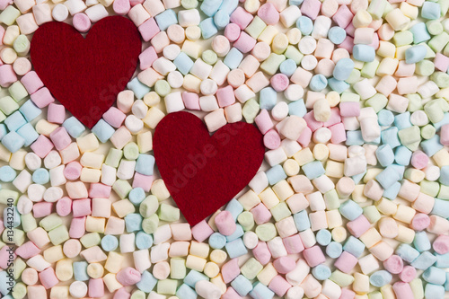 Two red hearts on colorful mini marshmallows background