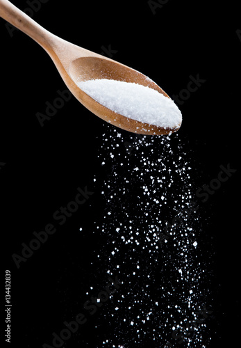 Картината върху платно Salt shaker,Sea salt on wooden spoon on black background