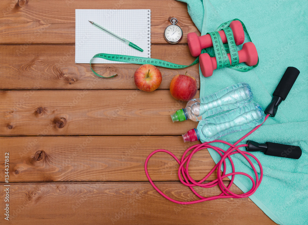 Fitness concept with dumbbells towel apples bottle of water