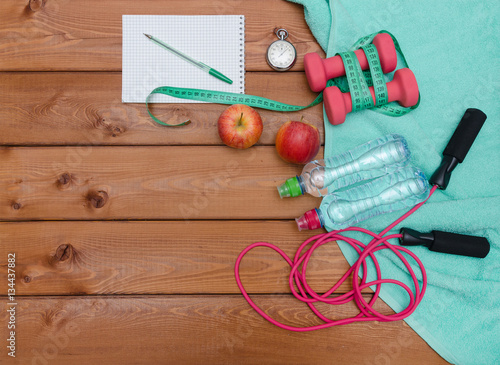 Fitness concept with dumbbells towel apples bottle of water