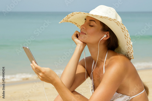Konstfotografi Beautiful woman listening music on the beach