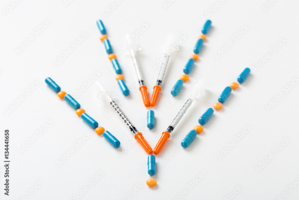 insulin syringe, pills and capsules in shape of down arrow