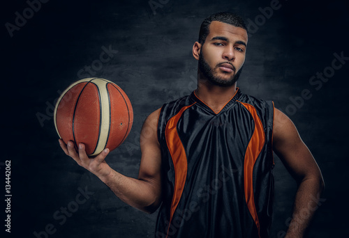 A black man holds a basket ball. © Fxquadro