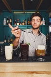 Young Barman offers cocktails in night club bar