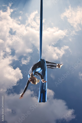 beautiful woman dancing with aerial silk on a sky background