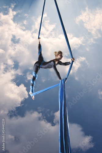 beautiful woman dancing with aerial silk on a sky background