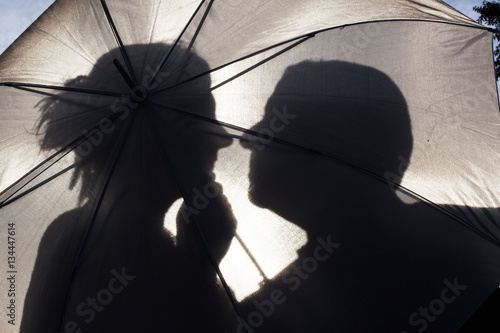 Jeunes mariés derrière une ombrelle à contre jour. photo