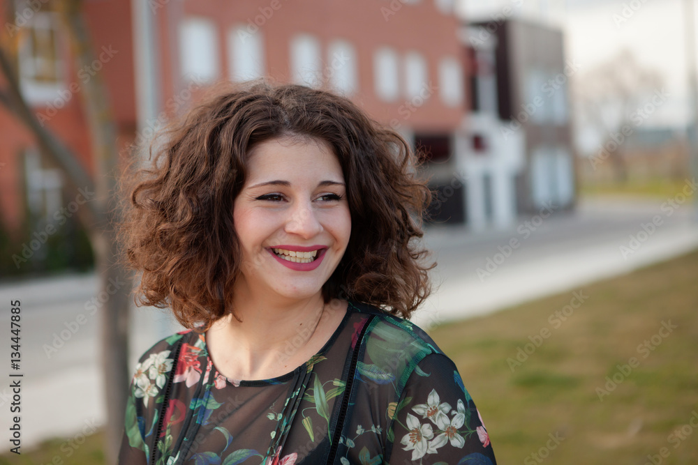 Fototapeta premium Happy curvy girl with curly hair in the street