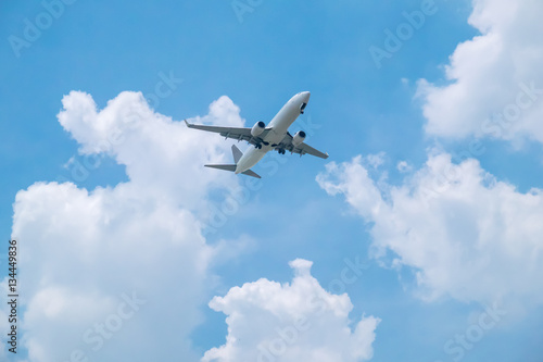 Airplane on bright blue sky background with white clouds