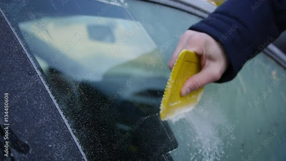 Autoscheibe der Tür mit dem Eiskratzer vom Eis befreien