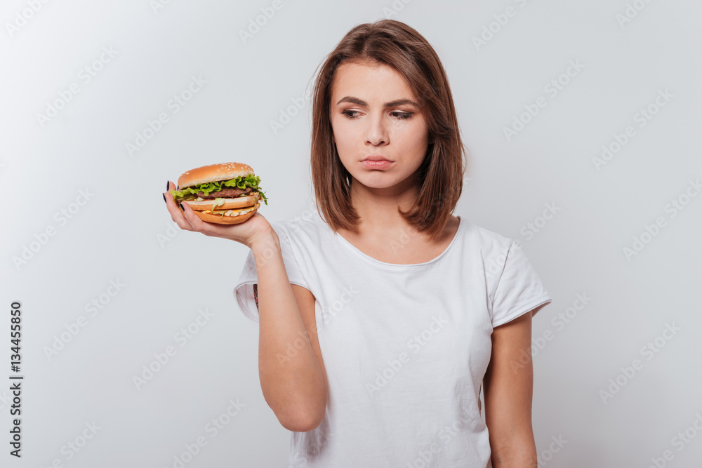 Confused young lady holding fastfood
