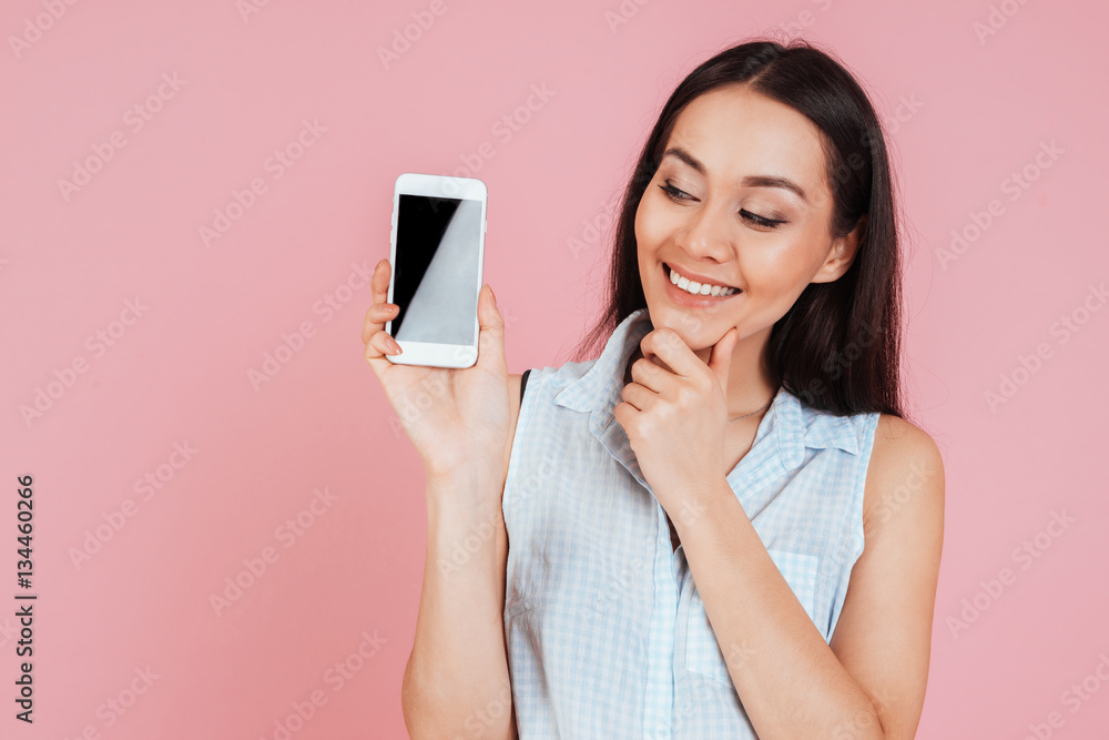 Woman showing and looking at blank smartphone screen Woman showing and looking at blank smartphone screen