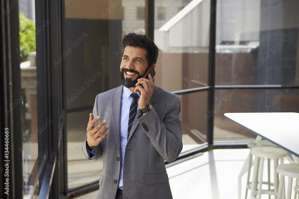 Smiling middle aged Hispanic businessman on phone in office Smiling middle aged Hispanic businessman on phone in office