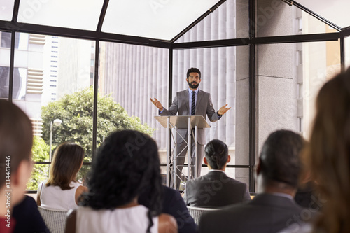 Hispanic man gesturing to audience at business seminar photo