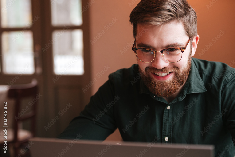 Happy bearded young man using laptop computer. Happy bearded young man using laptop computer.