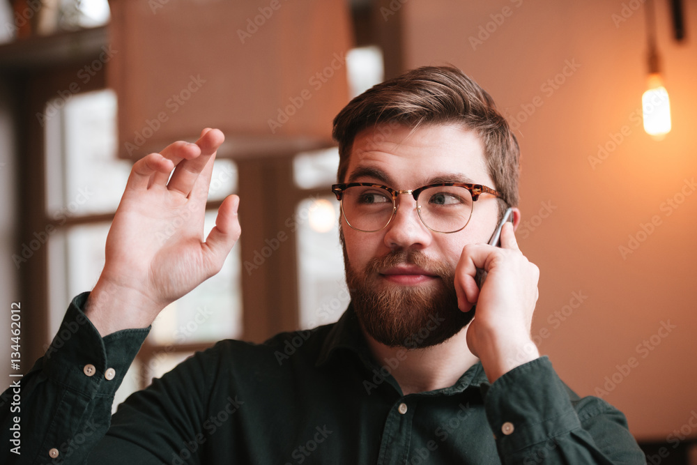 Young man talking by phone and waving look aside. Young man talking by phone and waving look aside.
